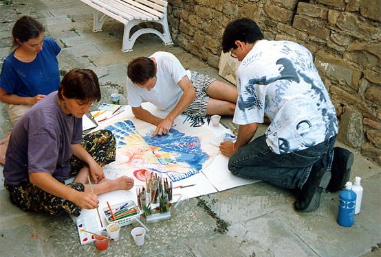 Four participants work together on a large painting outdoors.