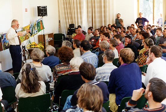 A speaker addresses a crowded and attentive lecture room.